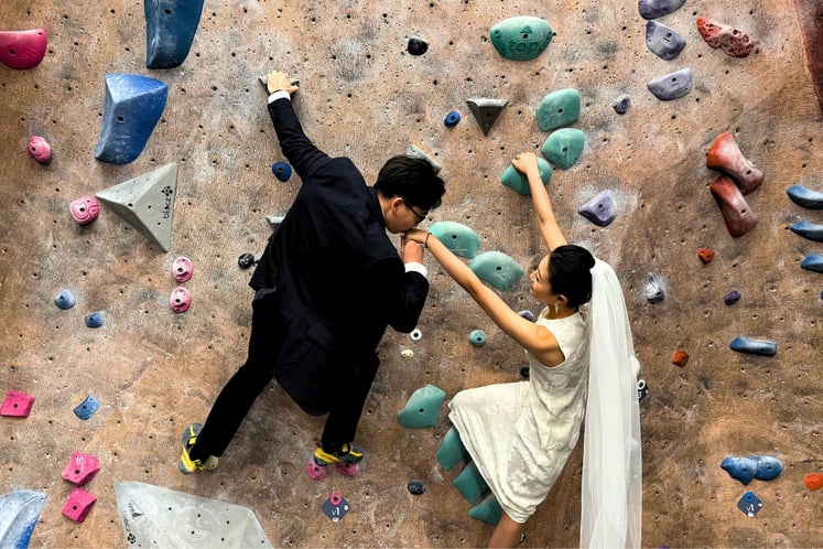 two climbers in wedding attire climbing on the wall