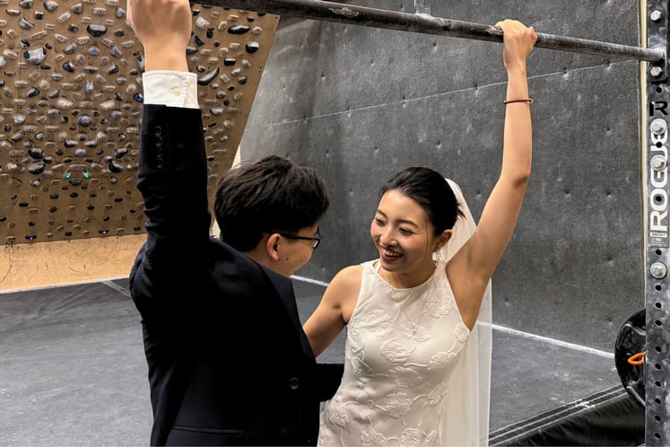 photo of two people hanging from a bar in wedding attire
