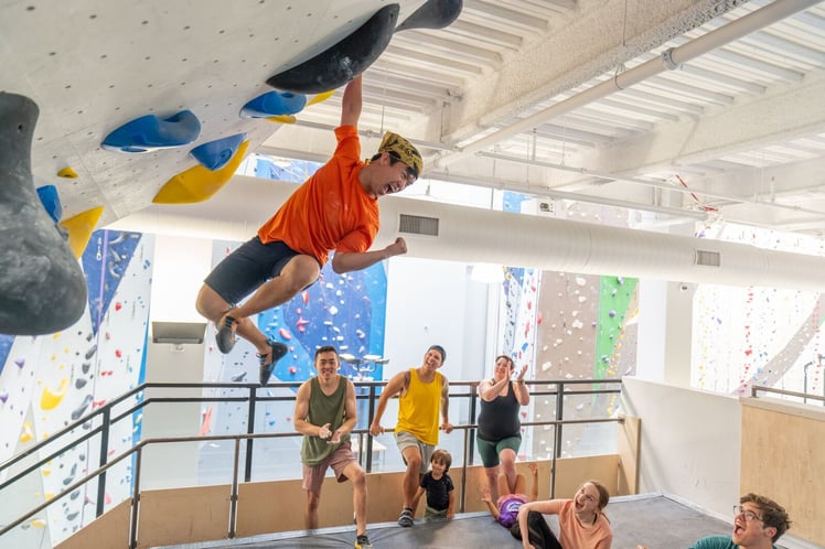 A new climber bouldering on a beginner-friendly route at a Movement climbing gym