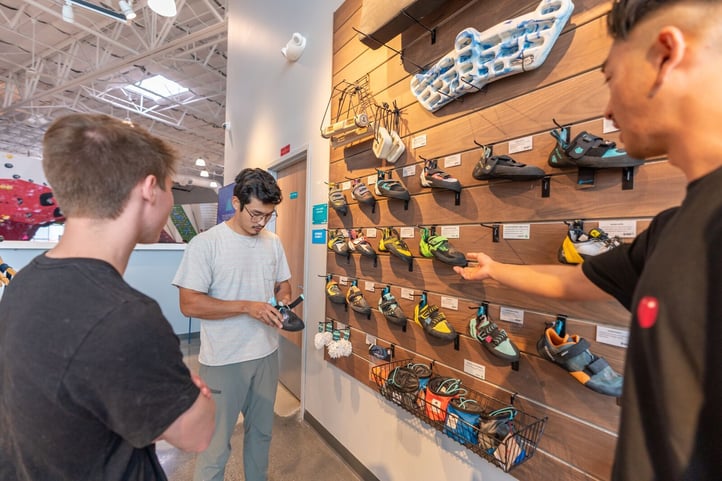 Climber looking at shoe display with friend and staff member