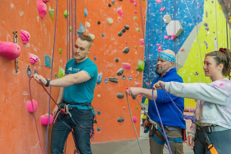 Climbing instructor showing students how to clip