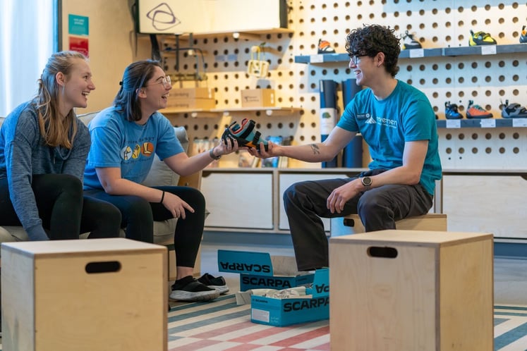 Two people trying on climbing shoes