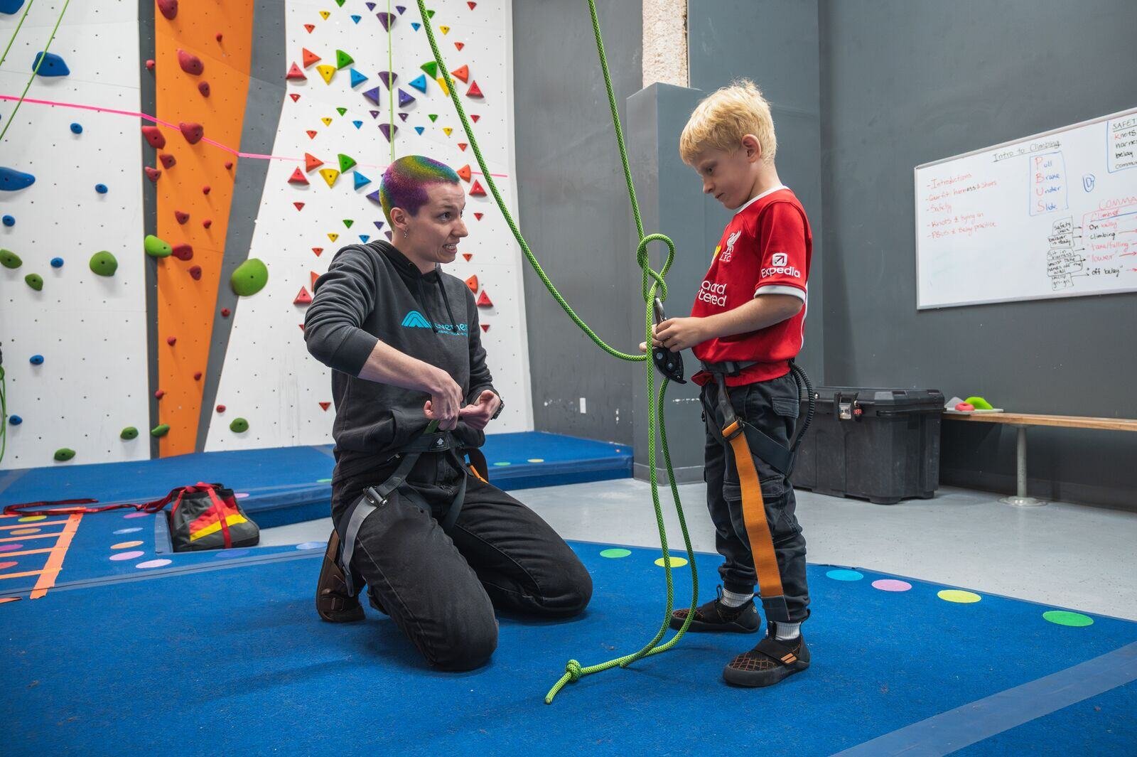 a youth climber learning how to tie in to a climb