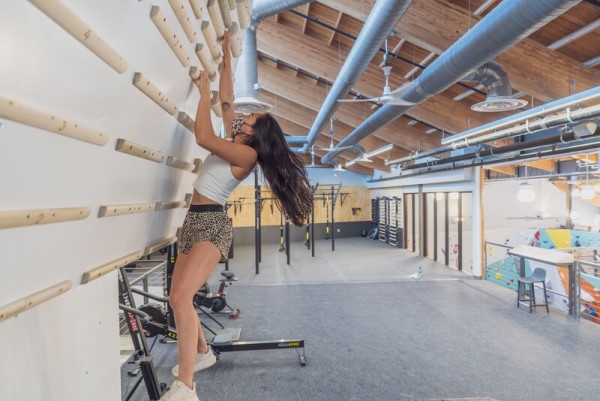Climber doing bump exercise on a campus board at Movement Gym.