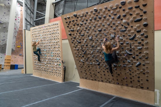 Climbers climbing on a Kilter Board (Left) & a Tension Board (Right)