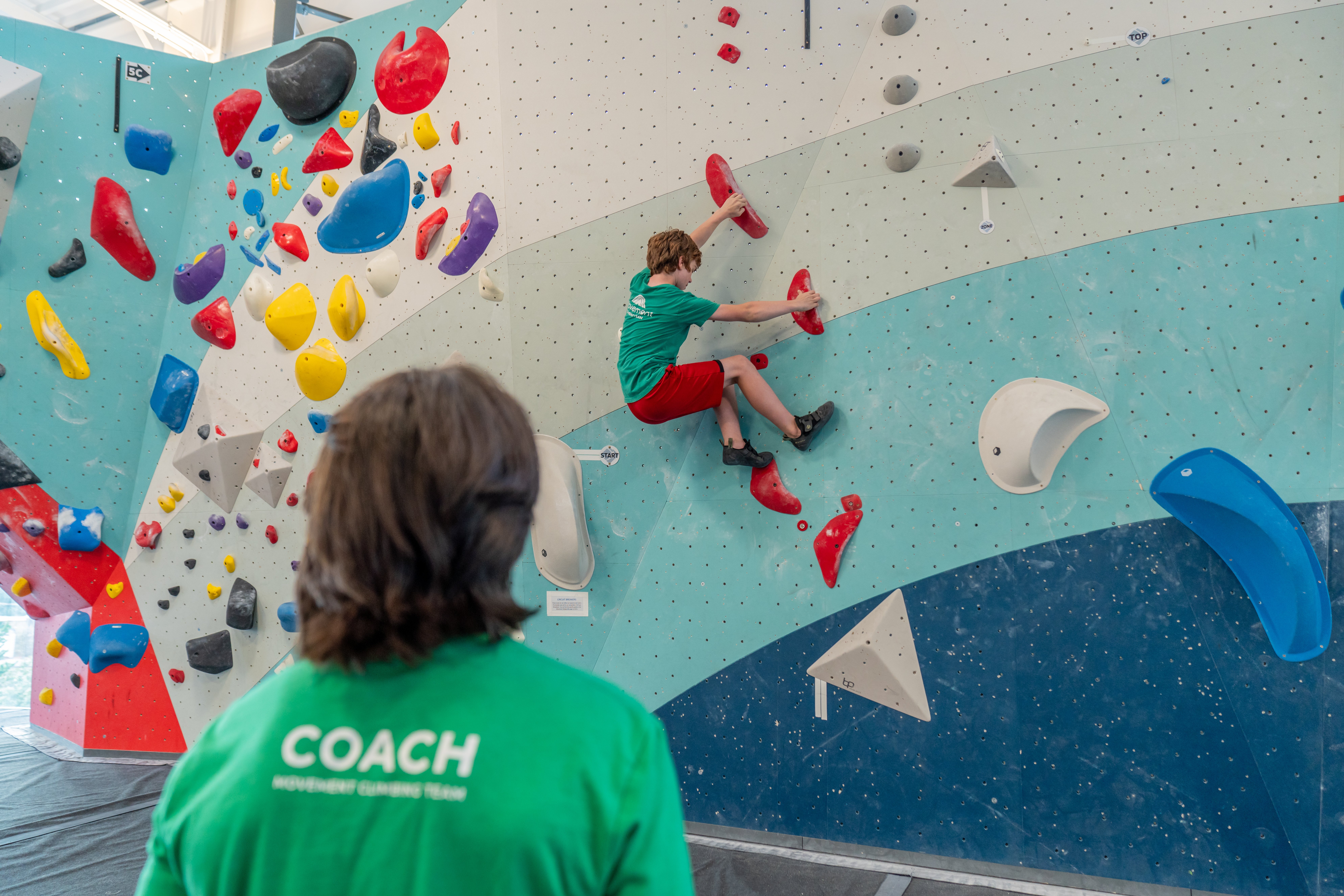 Climbing coach supporting a youth climber